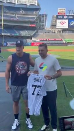 东契奇接过纽约洋基队球星阿隆-贾奇赠送的洋基队77号球衣